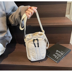 Détail du sac à cordon crème avec doubles fermetures éclair sur des marches en bois