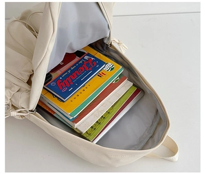 Interior view showing the large capacity of this cream white school backpack with textbooks