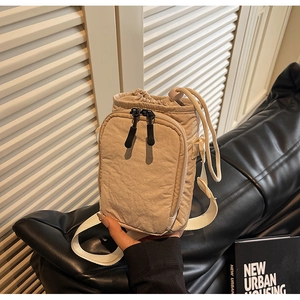 Détail du sac à bandoulière en nylon beige avec cordon de serrage et poche avant zippée