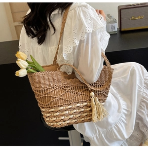Detalle del bolso tote bohemio de paja tejida con patrones calados y borla decorativa