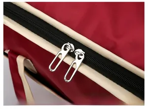 Detail view of burgundy travel bag with durable dual silver metal zippers and cream piping
