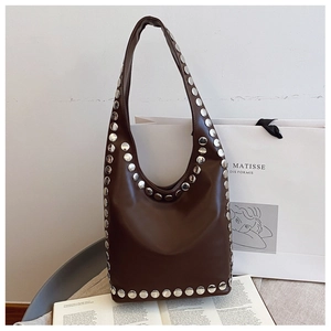 Detail view of vintage brown leather hobo bag with silver studs and artistic background