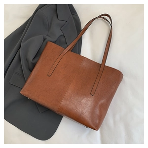 Detailed view of brown leather tote bag texture on a grey suit with metal studs