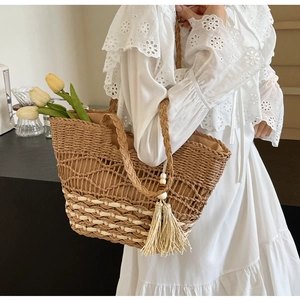 Detalle de bolso tote de paja tejida con textura ondulada y borla de flecos suave