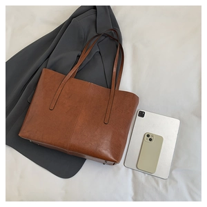 Brown leather tote bag featuring vertical stitching detail and durable metal feet