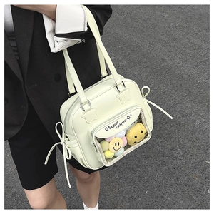Detail of light green tote bag with transparent front pocket and plush doll charms
