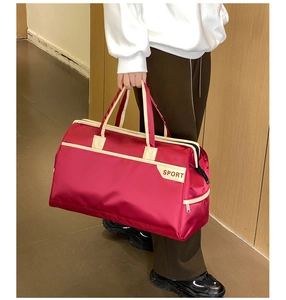 Detail of a red high-capacity travel bag with white sport handles and nylon texture