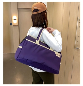 Purple large capacity sports travel bag with SPORT text worn by model in casual setting