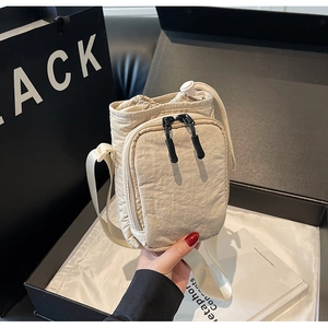 Détail d'un sac bandoulière en nylon beige avec cordon de serrage et sangle réglable