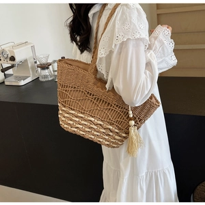 Detalle del bolso tote bohemio de paja con textura de malla tejida y colgante de borla