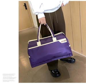 Close-up of a purple waterproof travel bag with ivory webbing and SPORT branding