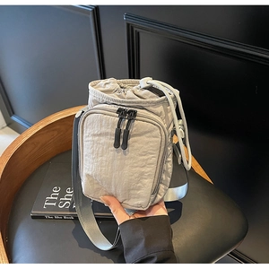 Détail d'un sac bandoulière en nylon gris clair avec cordon et poche zippée pratique