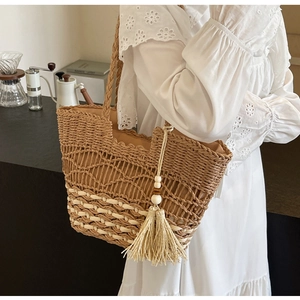 Detalle del bolso tote bohemio de paja con patrón geométrico y borla decorativa