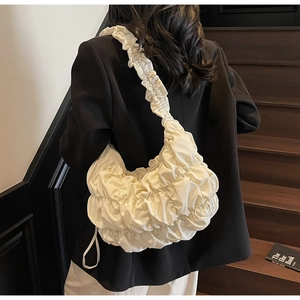 Dettaglio di una borsa a spalla plissettata bianco crema con texture morbida arricciata