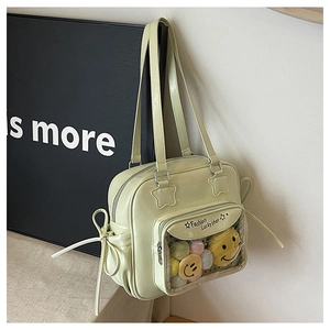 Detail of light green PU tote bag with star patch and plush smiley doll in PVC pocket