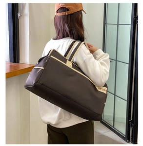 Detail of a brown sport travel bag with beige straps and a side SPORT logo