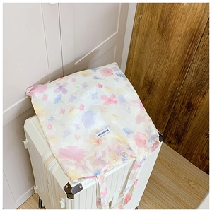 Dettaglio di una borsa tote floreale con motivi macaron colorati su una valigia