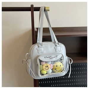 Detail of light blue tote bag featuring transparent window with plush smiley charms