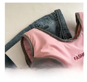 Gros plan d'accessoire rose avec bordure grise et broderie rouge sur fond en denim bleu