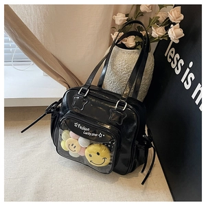 Detail of black glossy tote bag with transparent PVC layer and colorful plush charms