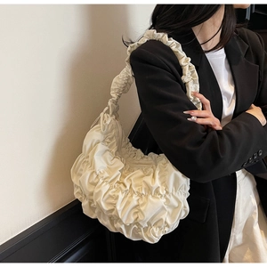 Dettaglio della borsa a nuvola plissettata bianco crema con texture trapuntata su blazer