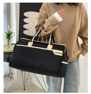 Detail of a large black travel bag with SPORT logo and beige contrast handles