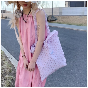 Close-up of floral tote bag with frilled edges and adjustable shoulder strap detail