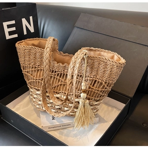 Detalle de bolso tote de paja bohemio con textura de ondas, borlas de madera y forro