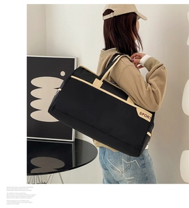Rear view of a model carrying a large black nylon travel bag with beige strap details