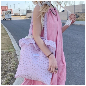 Close-up of a purple floral canvas tote bag with lace straps and ruffles detail