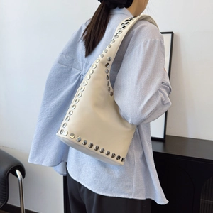 Cream leather hobo bag with large silver studs shown on model shoulder for daily style