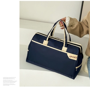 Detail of navy blue nylon travel bag with SPORT logo and cream handles for gym and travel