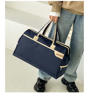 Detail of navy blue nylon travel bag with SPORT logo and beige handles for short trips