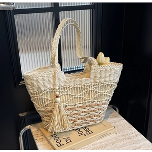 Detalle de bolso tote de paja bohemio con borlas de madera y textura de tejido hueco