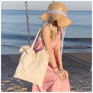 Floral cotton tote bag paired with wave-brim straw hat in a seaside sunset holiday scene