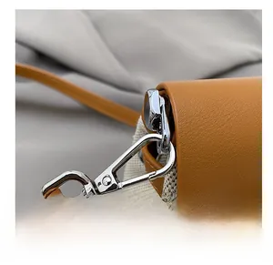 Macro detail of high-quality silver metal clasp on a beige canvas and brown leather bag