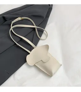 Detail of ivory elephant crossbody bag showing cartoon ear flap and slim leather strap