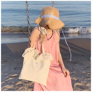 Close-up of a floral canvas tote bag and pink summer dress on a sunny beach