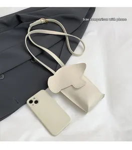 Close-up showing phone size comparison with elephant-shaped crossbody bag