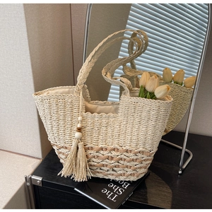 Detalle de bolso tote de paja bohemio con borlas de cuentas y fondo de contraste rugoso