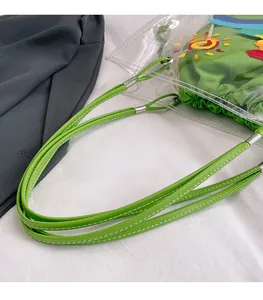 Detail of green leather handle with fine white stitching on a transparent PVC tote bag