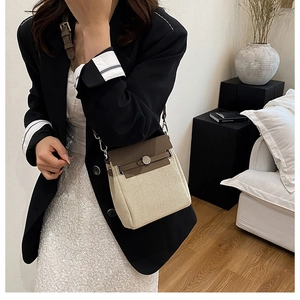 Detail shot of beige canvas and brown leather crossbody bag featuring metal buckle