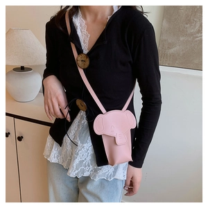 Detail of pink elephant-shaped crossbody bag worn over a black cardigan and white lace top