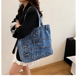 Detail of vintage blue denim tote bag with metal buttons and crisscross side lacing