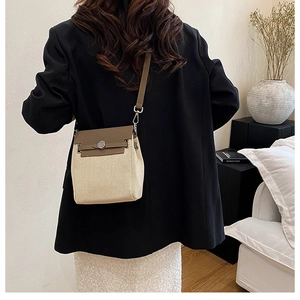Model wearing a retro canvas messenger bag with brown leather flap and silver buckle