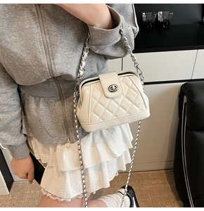 Dettaglio della borsa trapuntata bianca con catena e chiusura a rotazione sulla modella
