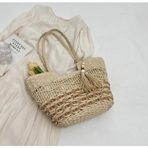 Primer plano de bolso tote de paja trenzada con borla y detalles de cuero natural