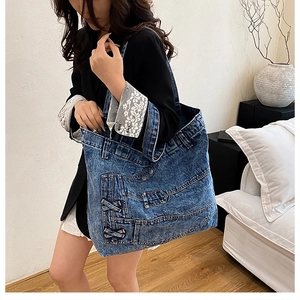 Detail of light blue denim tote bag with vintage wash, pockets and rivet accents