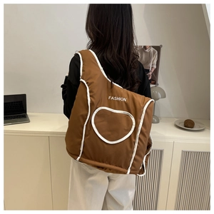 Détail d'un sac à dos matelassé marron avec liseré blanc et motif cœur fashion