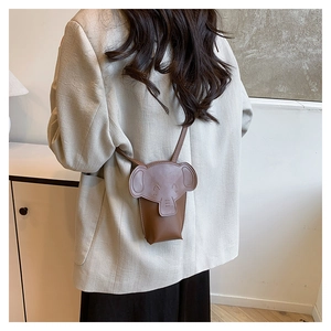 Detail shot of a brown elephant-shaped crossbody bag worn by a model in a minimal setting